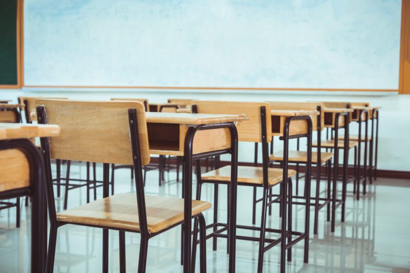 Lecture room, School empty classroom with desk chair iron wood for studying lessons in high school. No student in situation of Covid-19 disease outbreak result in inability organize teaching learning
