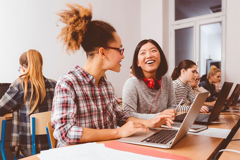 Girls studying on laptops and smiling