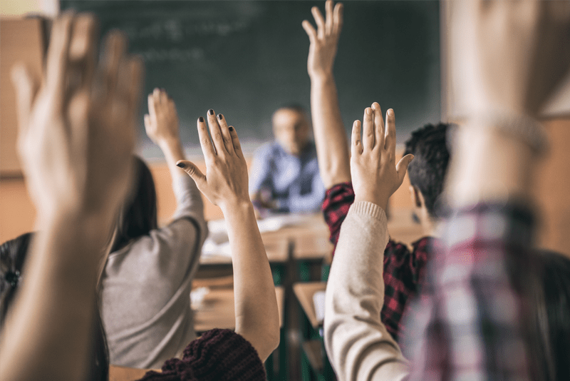A collection of raised hands in a classroom